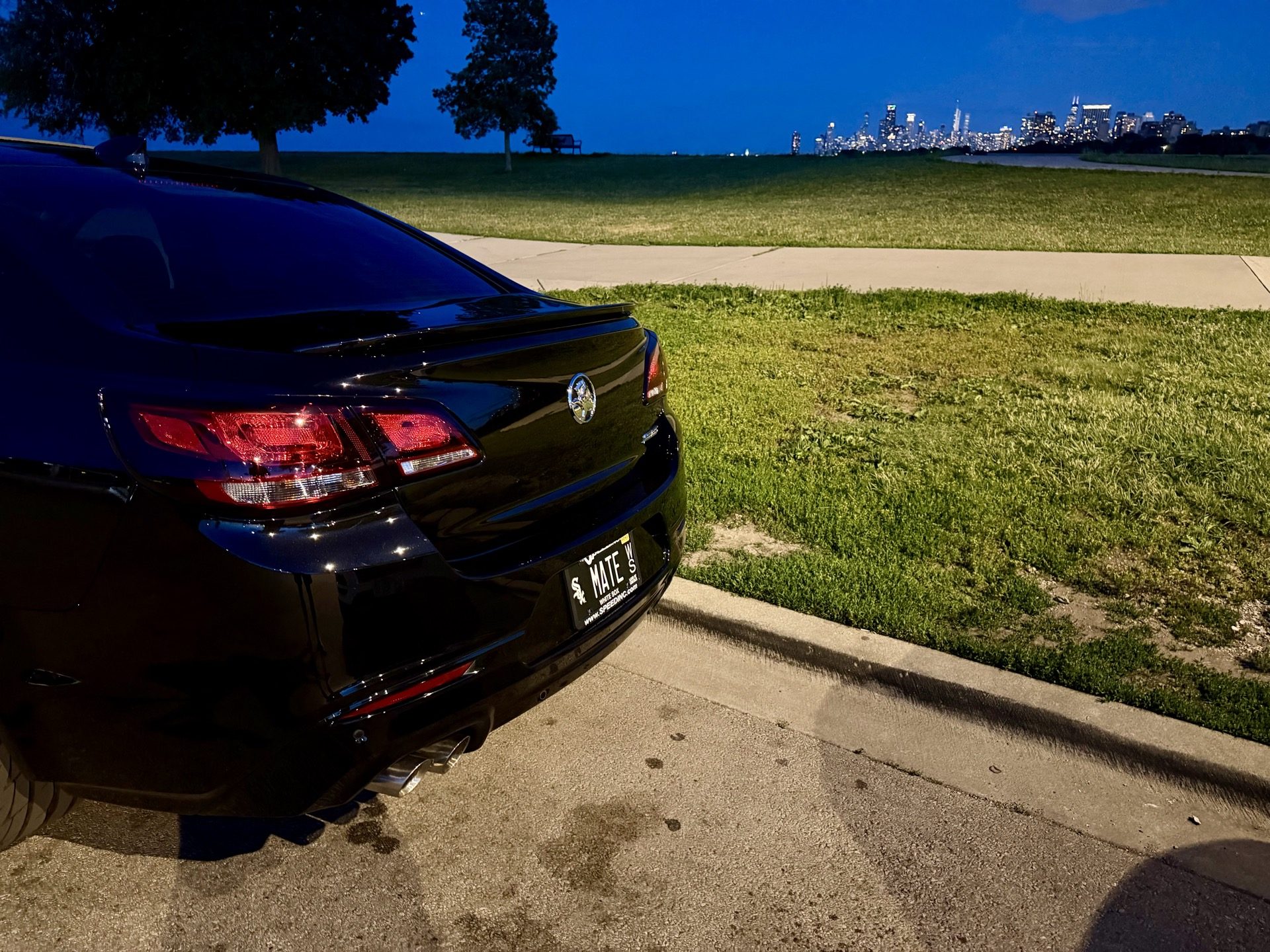 Close rear three-quarter shot of the Chevy SS showing the MATE license plate with the skyline in the distance