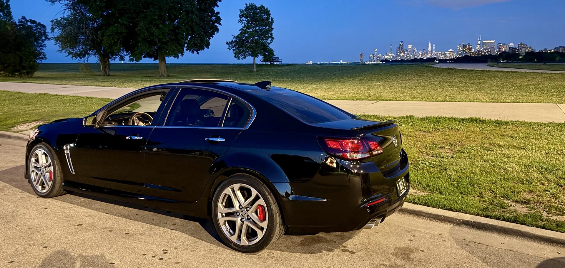 Rear three-quarter shot of the Chevy SS at Montrose Harbor with trees and the skyline behind it