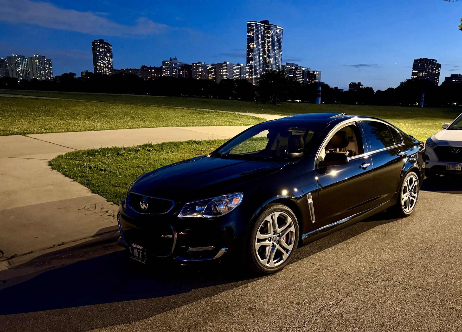 Front three-quarter shot of the Chevy SS parked at Montrose Harbor at dusk with the Chicago skyline behind it